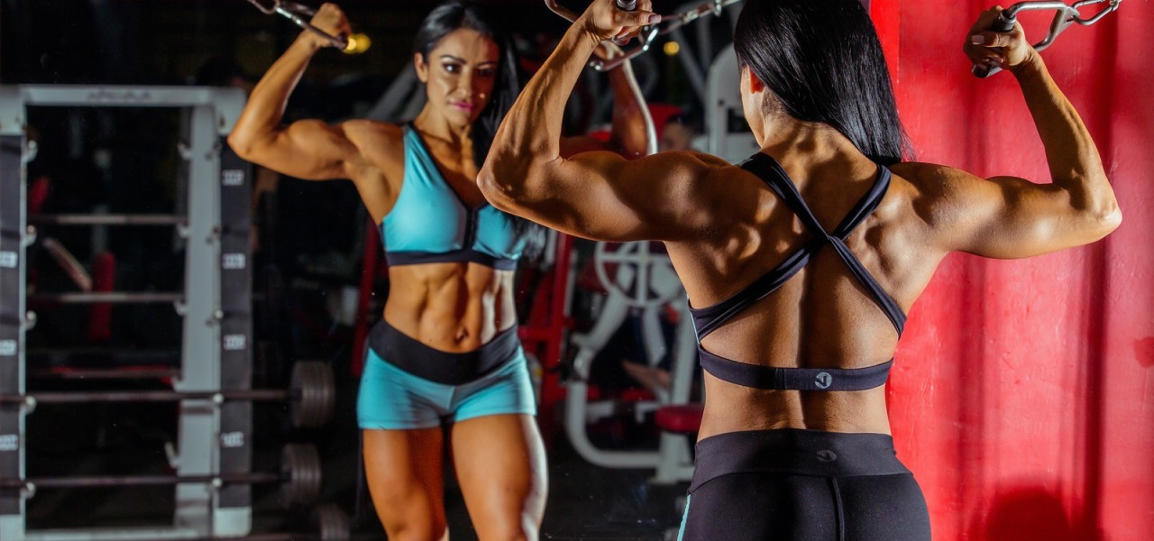 Photo Woman Bodybuilder Using Cable and Pulley Machine While Facing Mirror