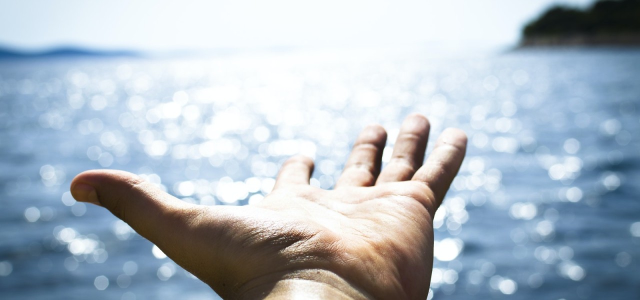 Person Hand Reaching Body of Water