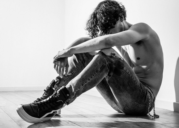 Grayscale Photo of Topless Man Sitting on Floor