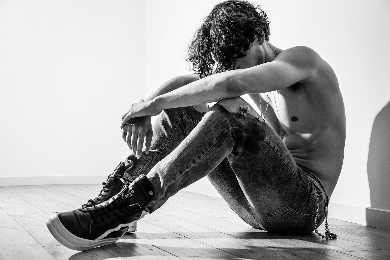 Grayscale Photo of Topless Man Sitting on Floor