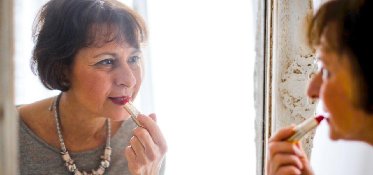 Photo of Older Woman Applying Lipstick In Front of the Mirror