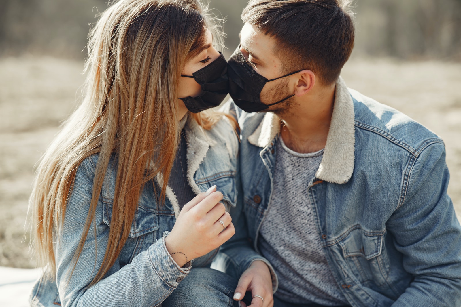 Loving young couple kissing while wearing black medical masks