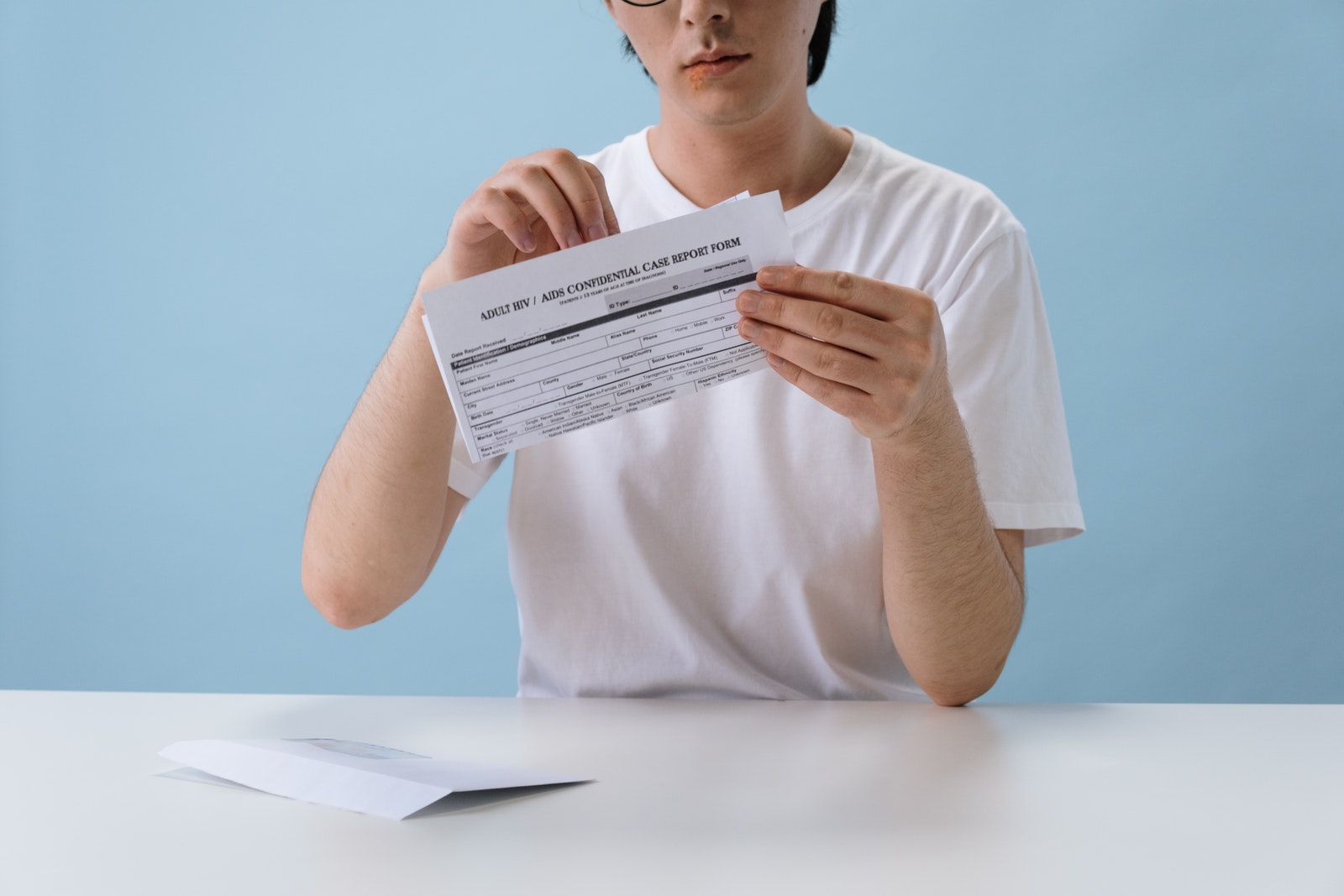 Man in White T-shirt Holding HIV/AIDS Paper Form