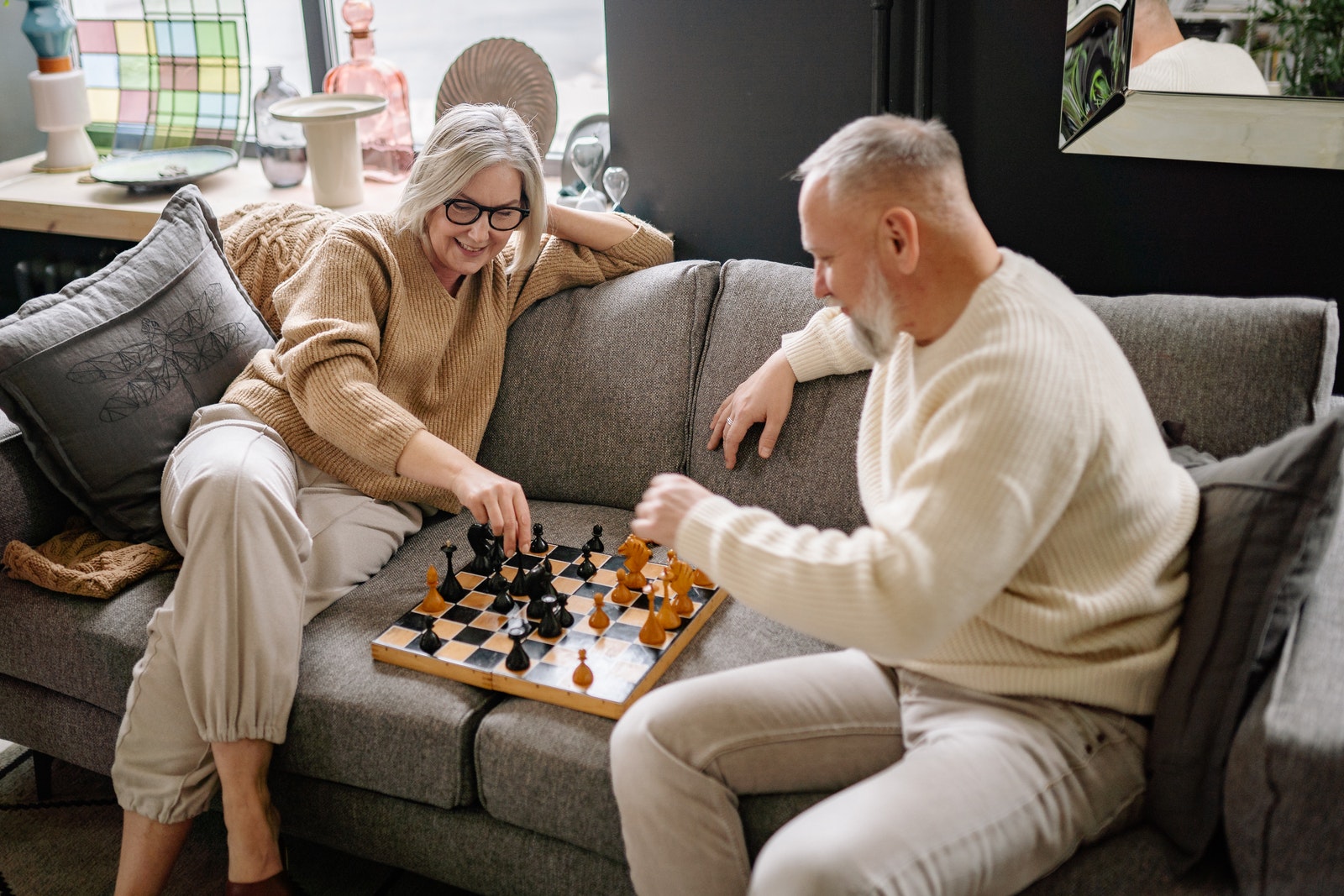 Couple Sitting on a Couch While Playing Chess