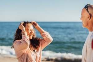 Woman in White Long Sleeve Shirt Holding Her Hair Near Body of Water