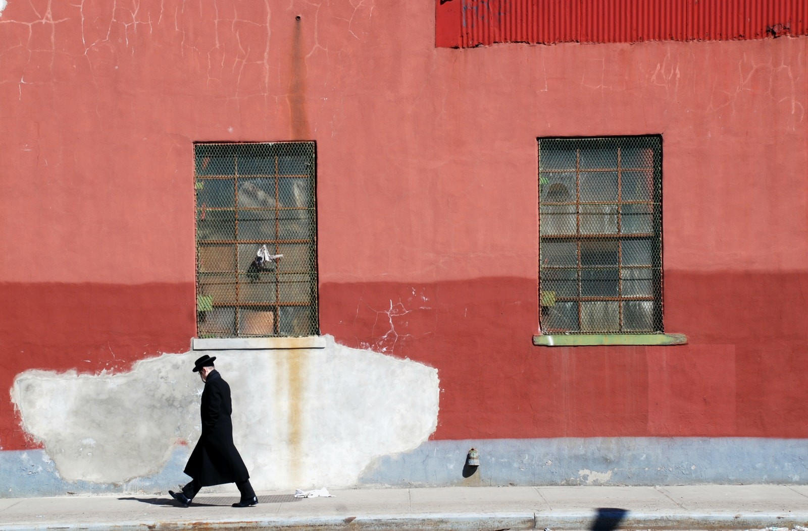 man walking beside red wall