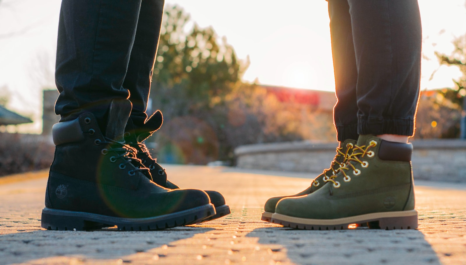 two people wearing green-and-black work boots standing on gray concrete pavement