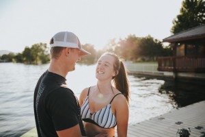 woman in white and black bikini top and white hat standing beside man in black shirt