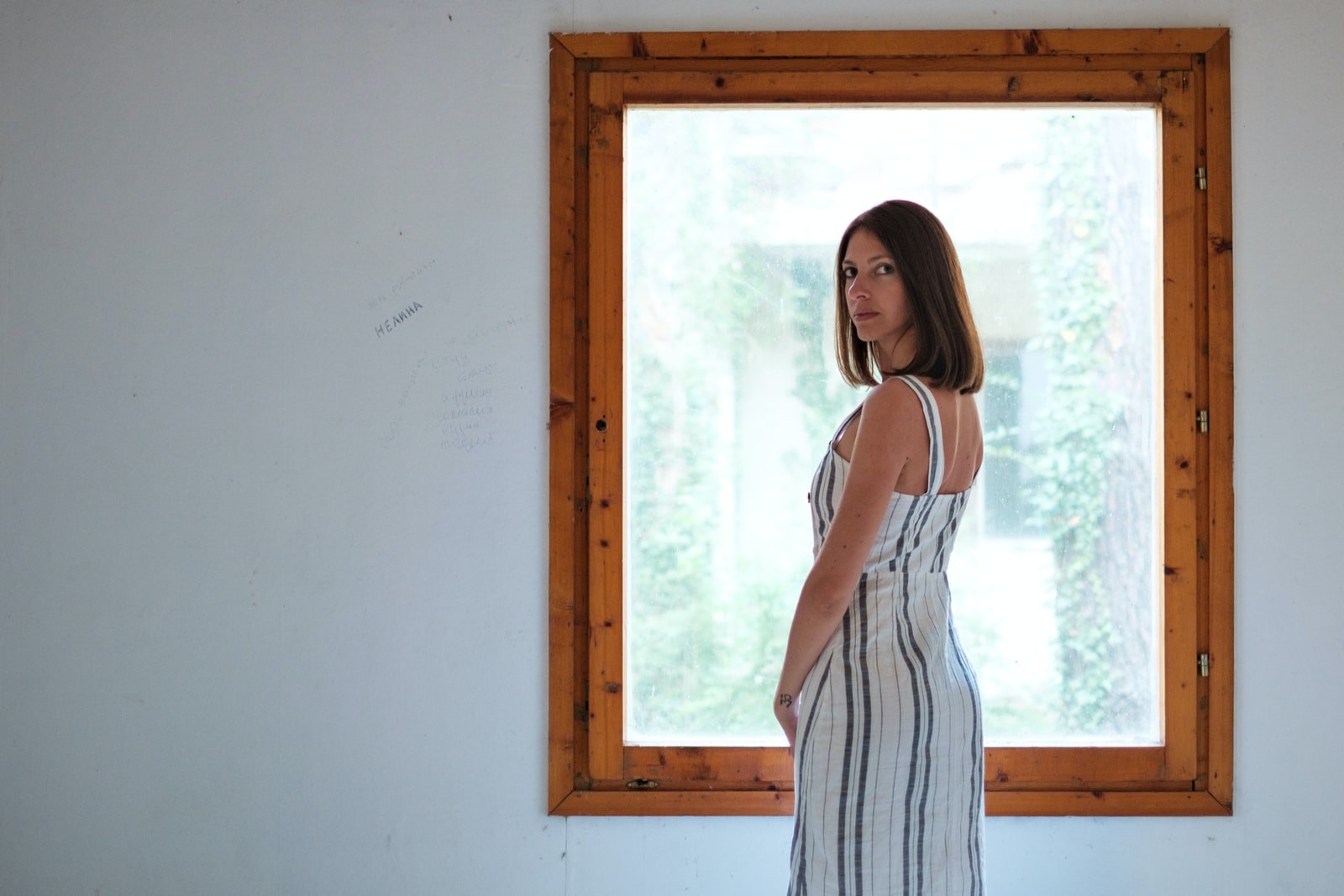 woman wearing white and blue pinstriped maxi dress i front of window